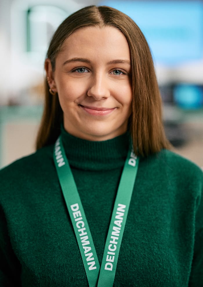 Junge Frau mit Namensband von Deichmann lächelt in die Kamera.